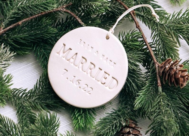 White round ceramic ornament with the text "Britt & Matt Married 7.16.22" embossed on the front.