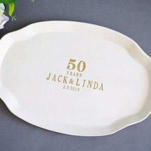 A white, oval-shaped serving platter with a wavy edge. Gold text reads "50 YEARS JACK & LINDA 2.9.2013". The platter is a wedding or anniversary gift.