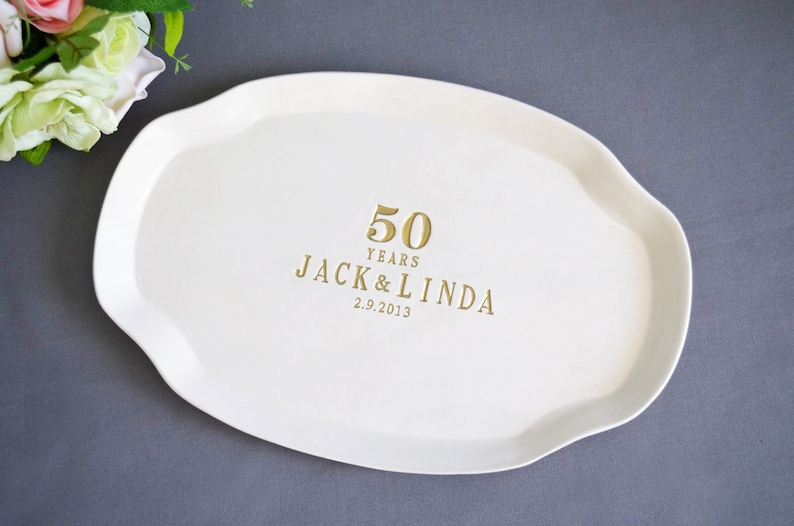 A white, oval-shaped serving platter with a wavy edge. Gold text reads "50 YEARS JACK & LINDA 2.9.2013". The platter is a wedding or anniversary gift.