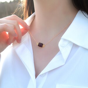 Puede incluir: Un collar de cadena dorada con un colgante rectangular negro.