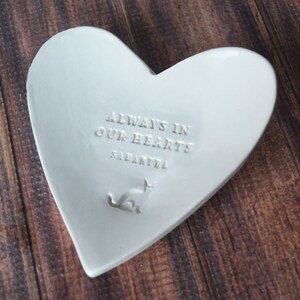 White ceramic heart-shaped dish with the inscription "Always in our hearts Samantha" and a small cat silhouette. Custom name.