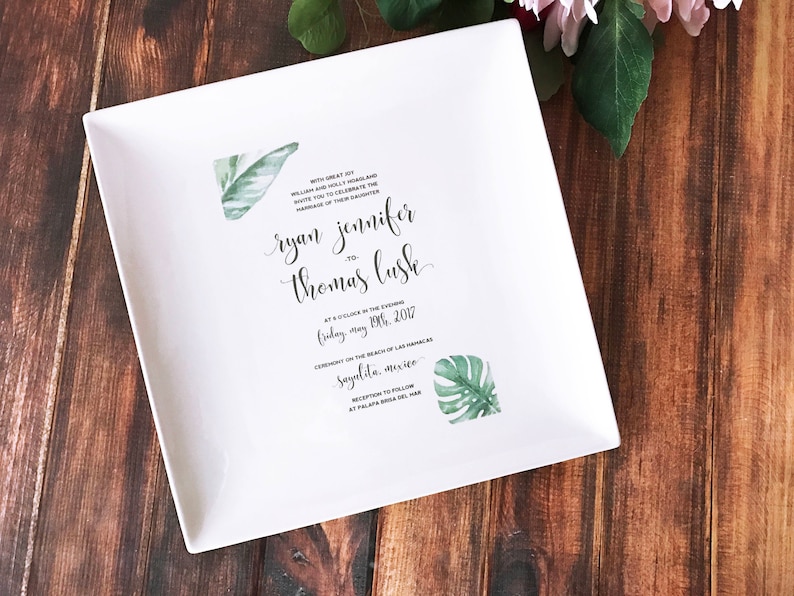 White wedding invitation imprinted on a square ceramic plate. The invitation is personalized to the special couple's big day.