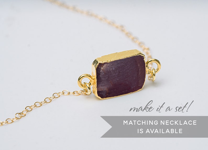 Puede incluir: Una pulsera de cadena dorada con un colgante rectangular de piedra preciosa p&uacute;rpura. El texto "make it a set! MATCHING NECKLACE IS AVAILABLE" est&aacute; debajo de la pulsera.