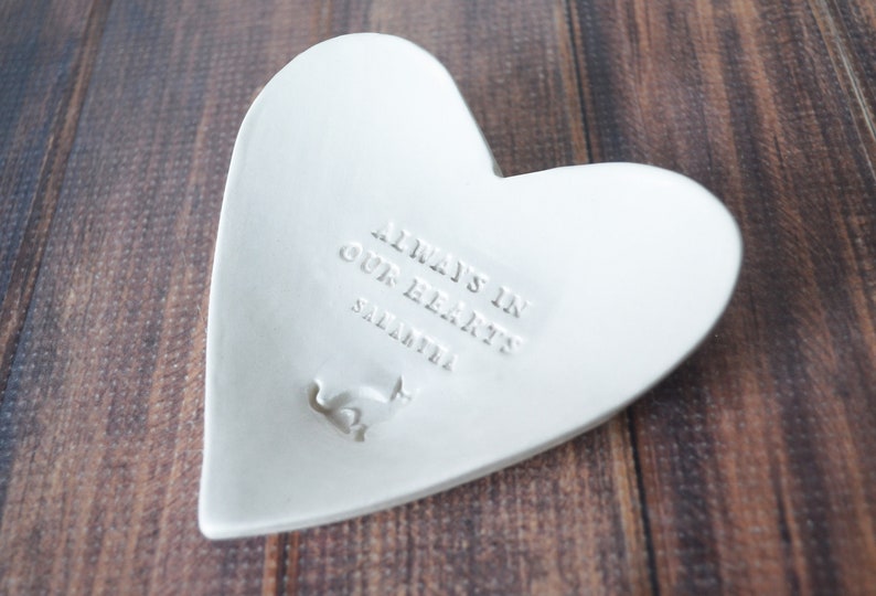 White ceramic heart-shaped dish with the inscription "Always in our hearts" and personalized with the pet's name