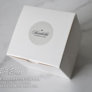 Op de afbeelding: Witte cadeaudoos met een zilveren sticker waarop "Jasabella" en "susabella.com" staat. De tekst "Gift Boxes" is in zwarte cursieve letters op de doos geschreven. De tekst "ARE AVAILABLE FOR PURCHASE. PLEASE SEE THE LISTING DESCRIPTION FOR BOX LINK." is in zwart onder de tekst "Gift Boxes" geschreven.