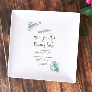 May include: White wedding invitation with green tropical leaf illustrations. The invitation reads "With great joy,  William and Holly Harris are delighted to celebrate the marriage of their daughter, Ryan Jennifer to Thomas Lusk, at 6 o'clock in the evening, Friday, May 19th, 2017, Ceremony on the beach of Las Marietas, Sayulita, Mexico, Reception to follow at Palapa Bonita del Mar."