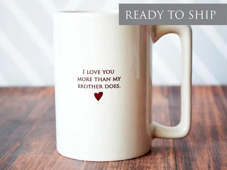 White ceramic coffee mug with a heart and the text "I love you more than my brother does."