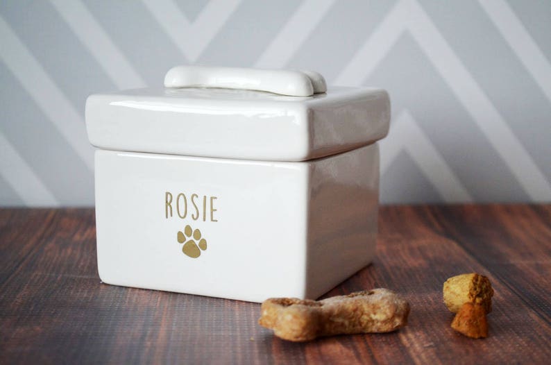 White ceramic pet food container with a bone-shaped lid. The container has the name "Rosie" and a paw print design in gold.