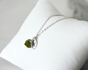 Puede incluir: Un collar de cadena de plata con una piedra preciosa verde y un dije de hoja de plata con la letra "K" grabada.