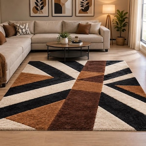 Può includere: Un tappeto rettangolare caratterizzato da un motivo geometrico con audaci strisce intersecanti nei toni del nero, marrone scuro, marrone chiaro e crema. Il design è composto da grandi triangoli e una fascia verticale centrale, creando un effetto visivo multicolore ad alto contrasto sull'intera superficie del rivestimento.