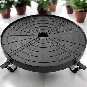 May include: A round black plant caddy featuring a grid pattern on the surface and a central circular opening. The base is supported by four swivel casters, each equipped with a locking lever mechanism to secure the position of the mobile stand.
