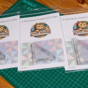 May include: Three clear acrylic quilting rulers for half square triangles in 1-inch, 2-inch, and 3-inch sizes. Each ruler is packaged in a clear plastic sleeve with a white card featuring the Ziggy Wiggles logo and text labels for the size.