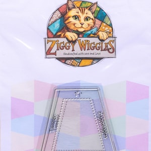 May include: A clear acrylic quilting template in a trapezoid shape, labelled 2 inches by 1 inch. The template features etched markings for cutting, including the text Ziggy Wiggles and Tumbler. The packaging displays a cat logo and SKU ZW117.