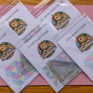 May include: Five clear plastic quilting rulers in sealed bags, each with a label featuring a cat logo and the text Ziggy Wiggles. The labels specify sizes including 1 inch Half Square Triangle, 4 inch Quarter Square Triangle, and 1.5 inch Equilateral Triangle.