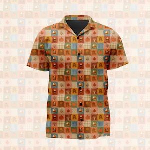 Pode incluir: Uma camisa de manga curta com botões e um padrão de xadrez patchwork em tons de laranja, castanho, azul e creme. O design inclui motivos repetitivos de abóboras, folhas de outono, cogumelos, girassóis e fatias de tarte de abóbora.