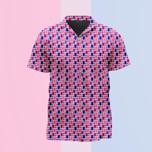 Puede incluir: Una camisa de manga corta con botones y un patrón geométrico repetitivo de pequeños rectángulos en tonos rosa, magenta y azul oscuro. La camisa tiene un cuello clásico, una tapeta frontal con botones a juego y un dobladillo recto.