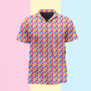Puede incluir: Una camisa de manga corta con botones que presenta un patrón geométrico repetitivo de pequeños rectángulos en tonos vibrantes de rosa intenso, amarillo brillante y azul cielo. La camisa tiene un cuello clásico, tapeta frontal y dobladillo recto.