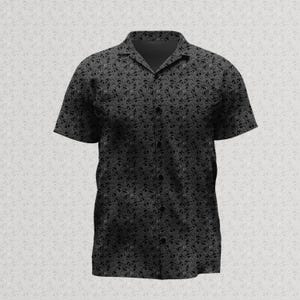 May include: A short-sleeve button-down shirt in a dark charcoal gray color featuring an all-over repeating pattern of small, intricate black paisley shapes. The shirt has a classic collar, a front button placket, and a straight hemline.