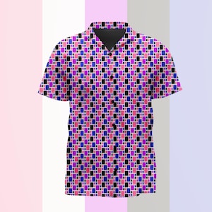 Puede incluir: Una camisa de manga corta con botones y un patrón geométrico repetitivo de pequeños rectángulos negros, azules y rosas. La camisa tiene un cuello clásico, una tapeta frontal con botones negros y un dobladillo recto en un diseño vibrante.