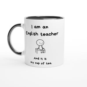 Puede incluir: Una taza de cerámica blanca con asa e interior negros. El frente presenta un dibujo lineal negro de una figura de palo sentada en un banco, con el texto "I am an English teacher" arriba y "And it is my cup of tea." impreso debajo de la figura.