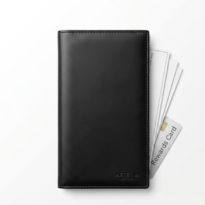 Op de afbeelding: Een zwarte leren chequeboekhoes met zichtbare stiksels langs de randen. In de rechterbenedenhoek staat de in reliëf gedrukte tekst AETERNA LEATHER. Verschillende witte papieren en een witte klantenkaart zitten in de zijkant van de hoes.