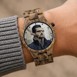 May include: A wristwatch with a brown wood grain finish on the case and link band. The watch face features a custom photographic print of a person wearing glasses and a dark jacket, with black hour markers and a bright yellow second hand.