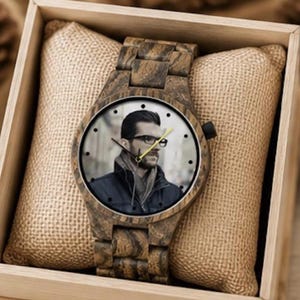 May include: A wooden wristwatch with a link band and a round face featuring a photographic portrait of a person wearing glasses and a dark jacket. The watch has black hour markers, black hour and minute hands, and a yellow second hand.