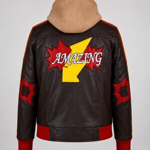 May include: A dark brown leather jacket featuring a tan hood, red ribbed cuffs and hem, and red and yellow sleeve stripes. The back displays a large yellow lightning bolt graphic with the word AMAZING in white text over a red starburst.