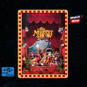 May include: A rectangular light-up sign featuring The Muppet Show logo in yellow text against a red curtain stage backdrop filled with various Muppet characters. The frame is bordered by a series of small, glowing light bulbs. Includes a USB icon.