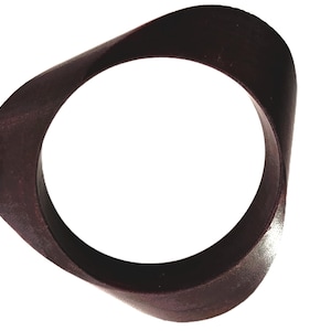 May include: A dark brown, circular ring with a smooth, matte finish. The object features a distinct, undulating, wave-like profile that creates a non-uniform thickness along its circumference, resulting in a continuous, flowing, and curved shape.