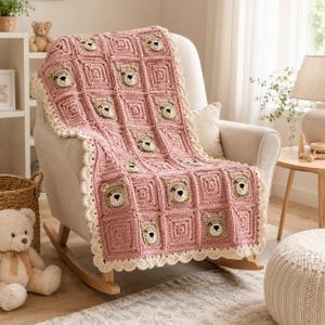 Può includere: Una coperta all'uncinetto color rosa polvere con un motivo ripetuto di quadrati, ognuno dei quali presenta al centro il muso di un piccolo orso marrone chiaro. La coperta è rifinita con un bordo smerlato color crema lungo i lati.