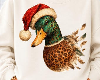 May include: A cream-colored sweatshirt featuring a graphic of a mallard duck wearing a red and white Santa hat. The duck has a green head, an orange beak, and a brown body with a leopard print pattern, surrounded by scattered feathers.