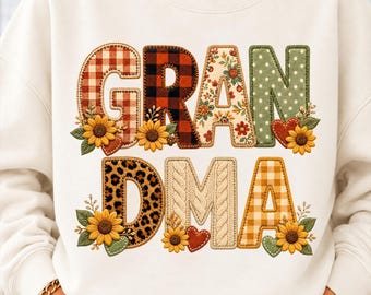 May include: A cream-colored sweatshirt featuring the word GRANDMA in large, patterned letters. Each letter has a unique design including red plaid, black plaid, floral, green polka dots, leopard print, cable knit, and yellow gingham, accented with sunflowers.