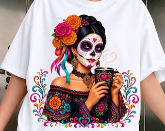 May include: A white t-shirt featuring a graphic of a person with sugar skull face paint, wearing a black off-the-shoulder top with floral embroidery. The person has orange and pink flowers in their hair and holds a black mug with a heart design.