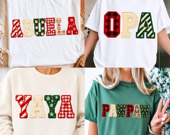 May include: Four shirts and sweatshirts featuring festive holiday-themed block letters. The designs include the words ABUELA, OPA, YAYA, and PAWPAW, decorated with patterns like red and green plaid, Santa faces, snowflakes, and Christmas trees.