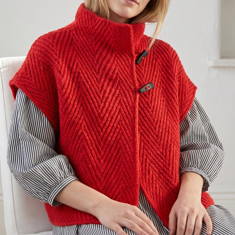 Woman wearing an oversized olive green herringbone knit vest with high collar
Textured knit waistcoat featuring decorative toggle buttons and sleeveless design
Modern knitted vest with herringbone stitch pattern and oversized silhouette
Warm merino wool vest layered over a long sleeve top with structured collar
Elegant button front knit vest featuring textured fabric and relaxed fit