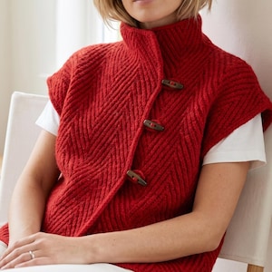 Woman wearing an oversized olive green herringbone knit vest with high collar
Textured knit waistcoat featuring decorative toggle buttons and sleeveless design
Modern knitted vest with herringbone stitch pattern and oversized silhouette
Warm merino wool vest layered over a long sleeve top with structured collar
Elegant button front knit vest featuring textured fabric and relaxed fit