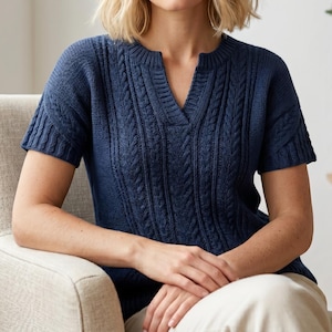 May include: A short-sleeved navy blue knit sweater featuring a vertical cable knit pattern on the front and a notched neckline. The garment has a ribbed collar and ribbed sleeve cuffs, with a textured knit construction throughout the bodice.