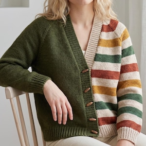 Pode incluir: Um cardigã de malha de manga comprida com um design de blocos de cor. O lado esquerdo é verde-azeitona escuro sólido, enquanto o lado direito e as mangas apresentam riscas horizontais em creme, amarelo mostarda, verde escuro e laranja ferrugem.
