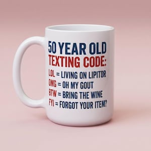 May include: A white ceramic mug featuring blue and red text that reads: 50 YEAR OLD TEXTING CODE: LOL = LIVING ON LIPITOR, OMG = OH MY GOUT, BTW = BRING THE WINE, FYI = FORGOT YOUR ITEM? The mug has a curved handle and a smooth, cylindrical body design.