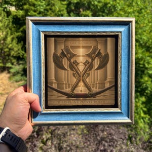 May include: A square framed print featuring a gold-toned illustration of two crossed battle axes and a bow set against a classical column background. The text "EARN THE THRONE" appears at the top and "DISCIPLINE PROVES WORTH" at the bottom.