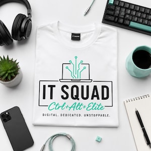 Op de afbeelding: Een wit t-shirt met een afbeelding van een laptop met printplaatlijnen, de tekst IT SQUAD, Ctrl+Alt+Elite en de woorden DIGITAL. DEDICATED. UNSTOPPABLE. Het zwarte neklabel bevat de witte tekst IT SQUAD.