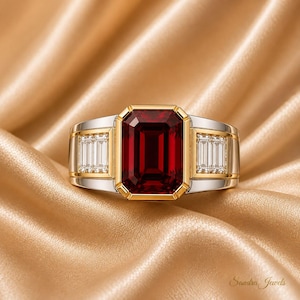 May include: A ring featuring a large emerald-cut deep red gemstone set in a gold bezel, flanked by two smaller baguette-cut clear stones on each side, all mounted on a wide silver-toned band with gold accents. The text Sandra Jewels is visible.