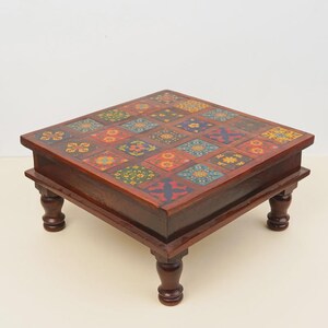 May include: A square wooden low table featuring a dark brown finish and four turned legs. The tabletop is decorated with a grid of twenty-five individual square tiles, each displaying unique, colorful floral and geometric patterns in various hues.