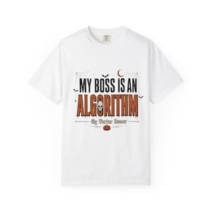 Puede incluir: Una camiseta blanca de manga corta con un gráfico que incluye el texto "MY BOSS IS AN ALGORITHM" y "Gig Worker Humor". El diseño presenta una calavera, una luna creciente, murciélagos, telarañas y una calabaza en tonos naranja y negro.