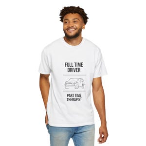 Puede incluir: Una camiseta blanca de manga corta con texto negro que dice FULL TIME DRIVER sobre un dibujo lineal de un SUV, seguido de otra línea y el texto PART TIME THERAPIST. El diseño está centrado en la parte del pecho de la prenda.