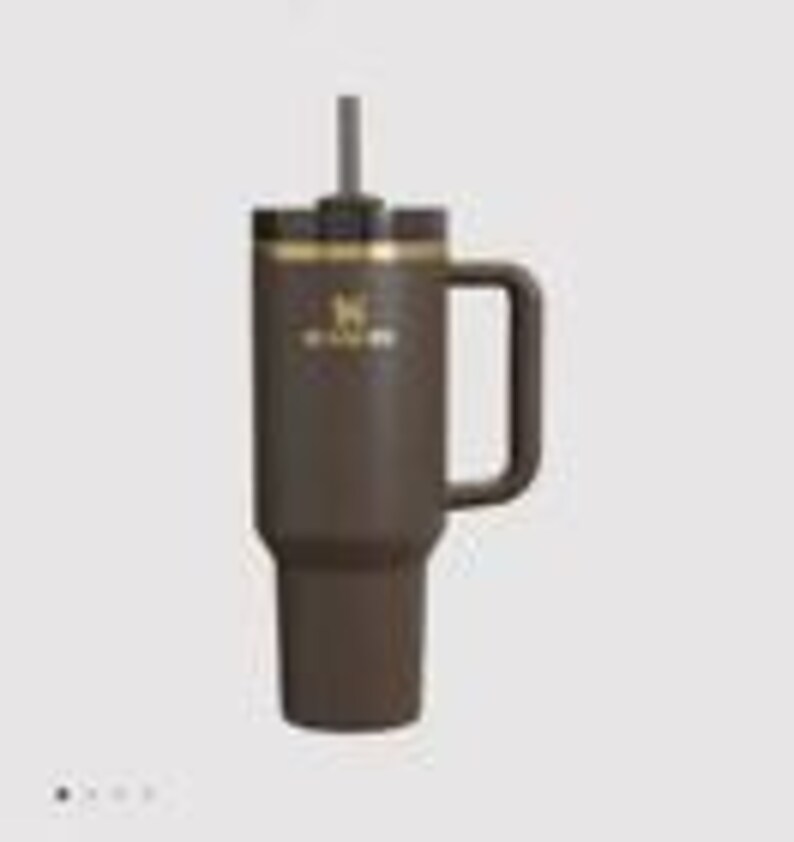 May include: A dark brown insulated tumbler with a matching handle, a black lid, and a central straw. The front features a gold-colored logo and the text STANLEY. The cylindrical body tapers at the base, designed for standard cup holders, with a matte finish.