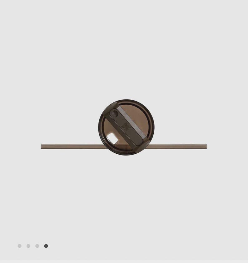 May include: A dark brown, translucent circular lid with a rotating closure mechanism and a matching dark brown straw extending horizontally through the center. The lid features a small, embossed logo detail on the top surface of the closure.