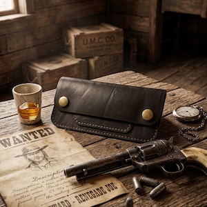 May include: A dark brown leather wallet featuring a rectangular flap secured by two brass-colored metal snaps. The wallet has visible stitching along the edges and a smooth, matte finish, presented as a functional accessory for carrying currency.