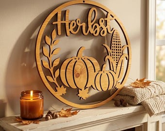 May include: A circular wooden wall sign featuring the word "Herbst" in cursive script, surrounded by cut-out designs of two pumpkins, a stalk of corn, and a leafy branch. The natural wood finish displays a visible grain pattern throughout the piece.